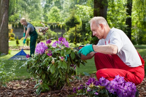 Gardener wearing PPE including gloves goggles and boots