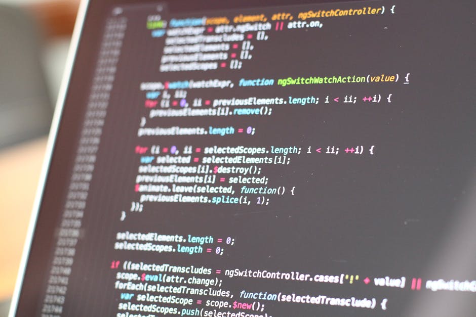 A close-up view of a person's hands operating a laptop with a dark screen displaying lines of colorful code, situated on a reflective black surface. The background is blurred, suggesting an indoor env